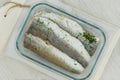 Marinated hake on a ceramic board on white background. Ready to cooking. Hake Filet. Top view.