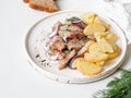 Marinated Herring fish with potatoes slices and red onion, rye bread on the white table Royalty Free Stock Photo