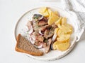 Marinated Herring fish with potatoes slices and red onion, rye bread on the white table Royalty Free Stock Photo