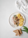 Marinated Herring fish with potatoes slices and red onion, rye bread on the white table. Top view Royalty Free Stock Photo