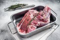 Marinated mutton lamb whole shoulder, raw meat in a steel tray with herbs and spices. White background. Top view. Copy Royalty Free Stock Photo