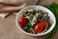 Marinated oyster mushrooms, garnished with cherry tomatoes and green dill. A dish with onions and butter in a white plate with a b