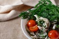 Marinated oyster mushrooms, garnished with cherry tomatoes and green dill. A dish with onions and butter in a white plate with