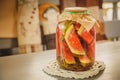 Marinated or pickled watermelon with herbs in a glass jar on a wooden table in a kitchen. Royalty Free Stock Photo