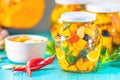Marinated preserving jars. Homemade orange cut pumpkin pickles with red hot chili peppers, fresh parsley, spices on light Royalty Free Stock Photo