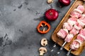 Marinated raw kebab on skewers, top view flat lay, with copy space for text, on gray stone table background