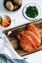 Marinated turkey steak with spices on a wooden board with carrot sticks and herbs on the table Royalty Free Stock Photo