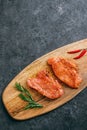 Marinated turkey steak on a wooden board with rosemary and chili pepper, copy space