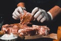 Marinating raw pork for cooking kebabs and ham. The chef of the restaurant in gloves treats the meat with basil and curry spices