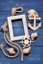 Marine attributes. Rope, frame, wooden anchor and steering wheel on a blue wooden background. Royalty Free Stock Photo