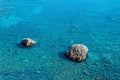 Marine background, transparent blue coastal littoral over coral reef and two rocks rise above the water