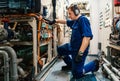 Marine engineer officer controlling vessel enginesand propulsion in engine control room ECR