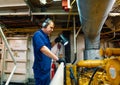 Marine engineer officer controlling vessel enginesand propulsion in engine control room ECR