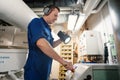 Marine engineer officer controlling vessel enginesand propulsion in engine control room ECR