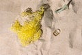 Marine litter on the beach, yellow plastic nest, broken glass and pop tops. Sunny flat lay arrangement