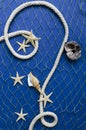 Vertical image. Rope, fishing net and starfish, seashell on it, blue surface Royalty Free Stock Photo