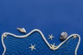 Marine rope as a symbol of sea wave, fishing net and seashells,starfish on the dark blue background.Empty space for text Royalty Free Stock Photo