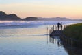 Marine scenery. Blue sea with mountains in horizona. A couple standing on the pier and small waves on blue water. Royalty Free Stock Photo