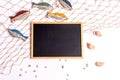 Marine still life: an empty board on a sea net, wooden fish and seashells on a white background Royalty Free Stock Photo