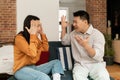 Marital problems, divorce concept. Married japanese couple having fight, yelling at each other, sitting on sofa at home Royalty Free Stock Photo
