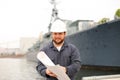 Maritime engineer looking at blueprints and standing near vessel. Royalty Free Stock Photo