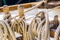 Maritime nautical ropes, knotted on wooden cleats of old sailing boat