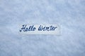 Marker inscription hello winter on  a of white fluffy snow  background, snow texture background Royalty Free Stock Photo