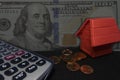 Money,calculator,coins bank with red house model on table