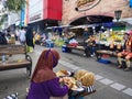a market that is quite busy with people and there are chicken satay sellers serving customers