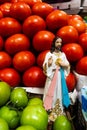 Religious figure in the middle of red and green tomatoes at a market stall