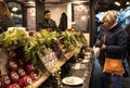 Market stall vendor selling cheeses on the street showing display and taster samples with customers