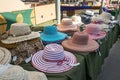 Market stall vendor selling fashion accesories and large sun hats for ladies