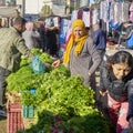 Market stall with a young girl and an elderly woman selling herbs such as dill, peppermint, parsley and radishes