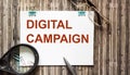 Marketing notes notebook. DIGITAL CAMPAIGN text on wooden table Royalty Free Stock Photo