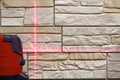 Marking a wall using a laser level. Red beam on a stone wall. Repair and construction. Royalty Free Stock Photo