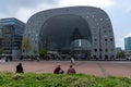 The Markthal building and train station with people relaxing and the city square in the foreground