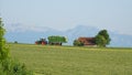 Marktoberdorf, Germany. Green fields with grass and hay cut ready to be harvested. Fendt tractor with hay collection Tigo trailer