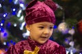 Marmalade bear. Emotional boy three years old in a purple bear costume on the background of a New Year tree and blue lanterns Royalty Free Stock Photo