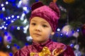 Marmalade bear. Emotional boy three years old in a purple bear costume on the background of a New Year tree and blue lanterns Royalty Free Stock Photo