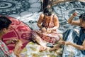 Maroochydore, Australia - February 15, 2020. Females weaving baskets on craft workshop, sitting on carpet in park.