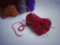 Maroon knitting wool and crochet hook with on a background of colorful wool yarn, vintage style