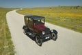 A maroon Model T driving down a scenic road surrounded by spring flowers off of Route 58, Shell Road, CA