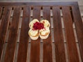 A maroon rose blooms on top of cream muffins on a wooden countertop on a Sunny summer day. Confectionery on display.