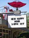 Marque and red lips neon sign advertising new happy hour times.