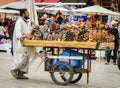 A Moroccan male vendor pushing a trolley with colorful shoes at Marrakech Jemaa el-Fnaa Square