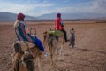 Marrakech, Morocco - Feb 22, 2023: Tourists ride Dromedary camels through the Agafay desert