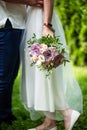 Marriage couple legs standing together on green lawn, bride holding wedding bouquet. Bride and groom. Royalty Free Stock Photo