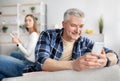 Marriage infidelity or gadget addiction. Mature man using smartphone to text lover, his wife with mobile device indoors Royalty Free Stock Photo