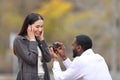 Marriage proposal of interracial couple in a park Royalty Free Stock Photo