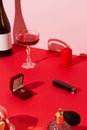 Marriage proposal valentines day concept. Ring, sparkling wine, glasses,candies and cosmetics on red table